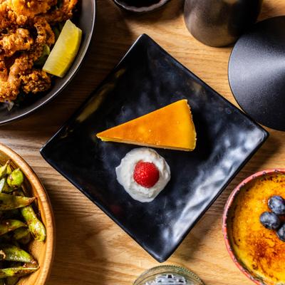 Yuzu cheesecake slice beside blueberry-topped creme brulee.