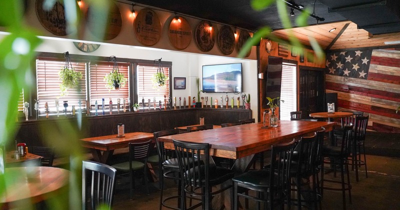 Rustic bar and dining area with wooden tables, plants, and American flag decor