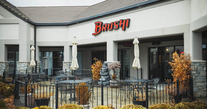 Exterior, front of a restaurant, entrance and sign above, garden tables and chairs in front