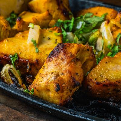 Chicken tikka kabab on a sizzling platter, close-up.