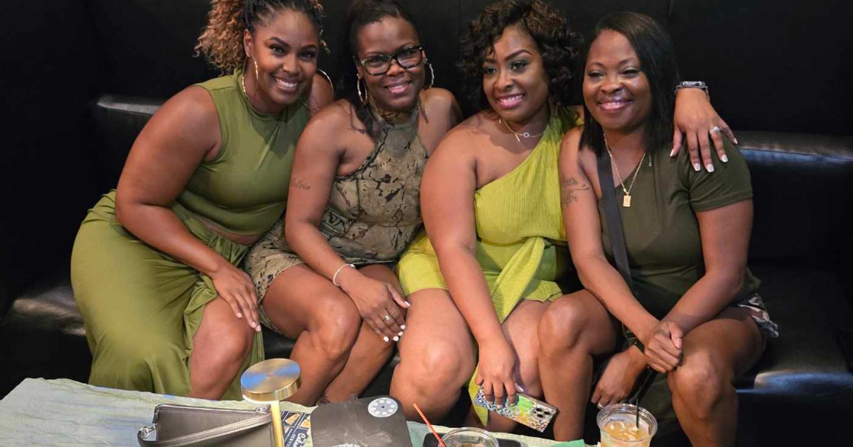 Interior,  group of smiling friends posing together for the shot on a leather sofa