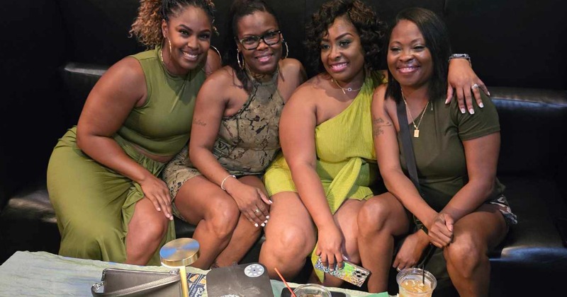 Interior,  group of smiling friends posing together for the shot on a leather sofa