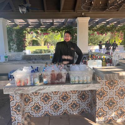 Outdoor bar with bartender and ice bins.