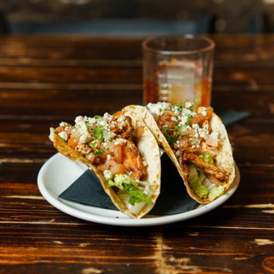 Black and bleu salmon tacos with onions and cheese.
