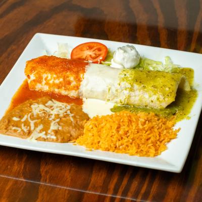 Burrito macho served with rice, refried beans, sour cream, lettuce, and a tomato slice.