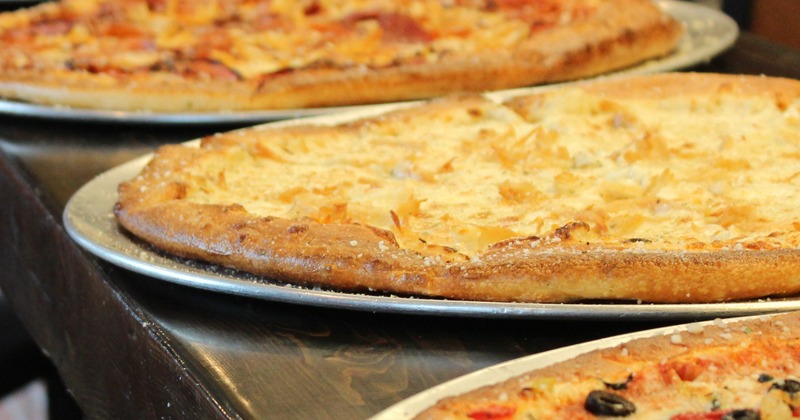Multiple pizzas in a row on a counter