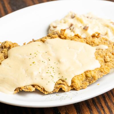 Fried steak with gravy and mashed potatoes.