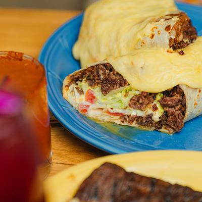 Cheese-covered beef burrito on a blue plate.