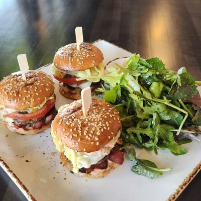 Three mini burgers accompanied by a fresh mixed green salad.