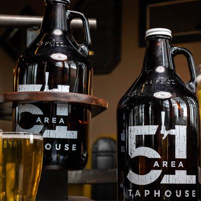 Two dark glass beer growlers labeled 51 Area Taphouse beside a pint of beer.