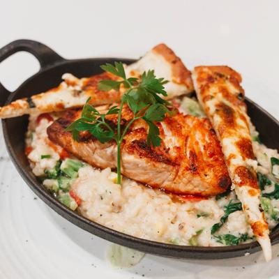 Grilled salmon served over a bed of rice with grilled pita