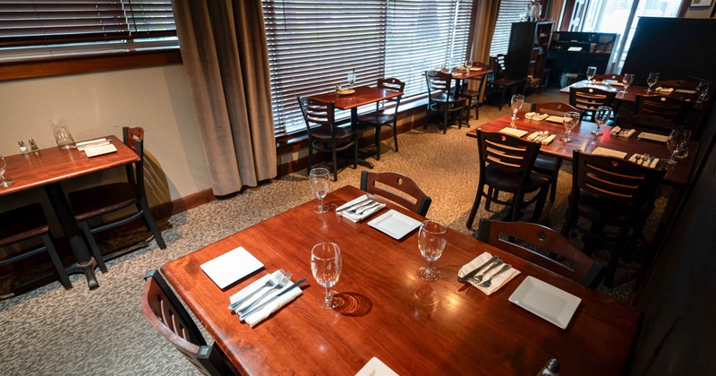 Cozy restaurant interior with wooden tables set elegantly with white dishes