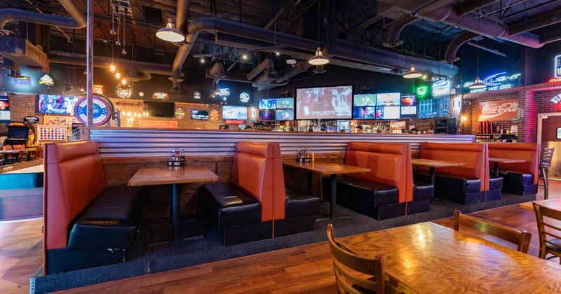 Interior, red leather padded seating booths with tables, wood flooring, vent tubes on the ceiling