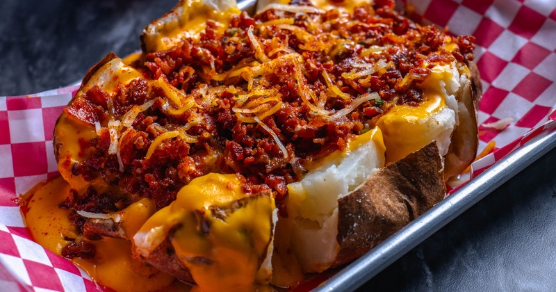 Baked potato, with garlic butter, bacon, shredded cheese, and cheese sauce