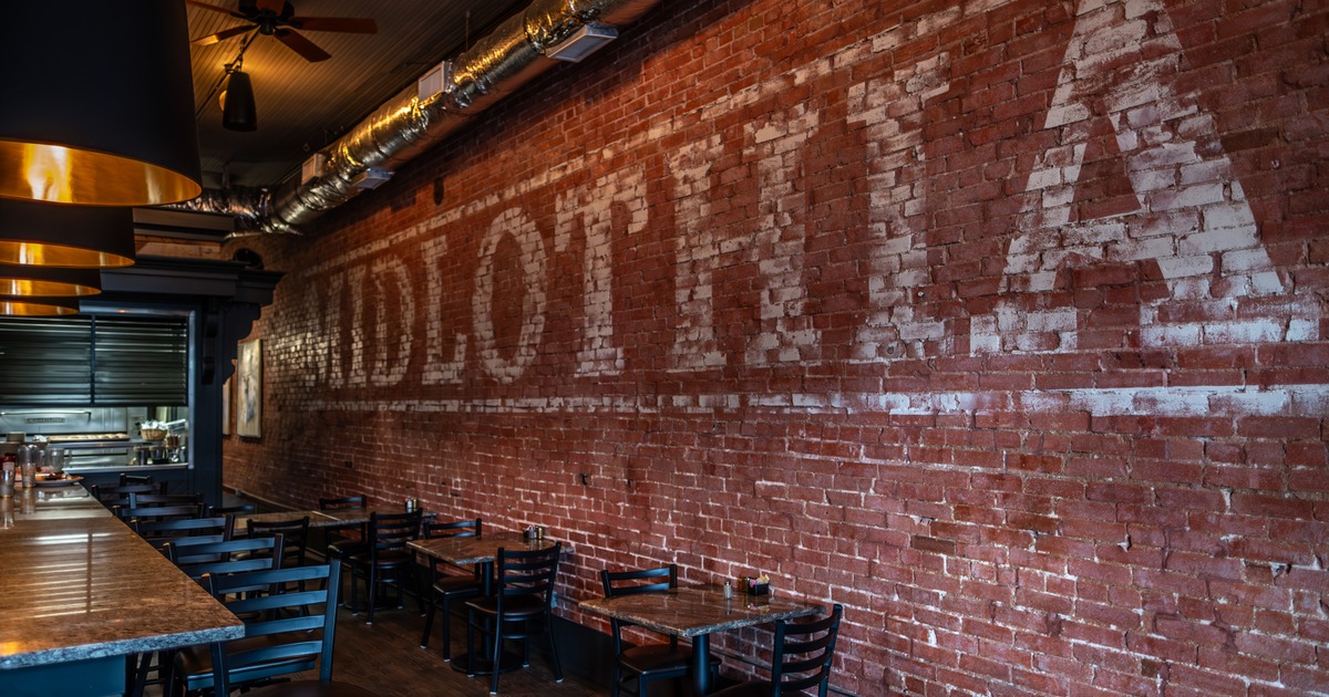 Brick wall with sign, tables and chairs in front