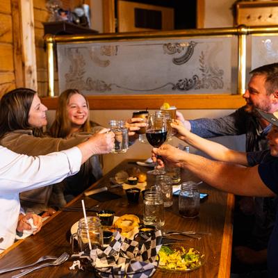 Interior, a group of people clink glasses at table.