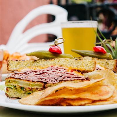 Fried green tomato and ham sandwich served with a beer