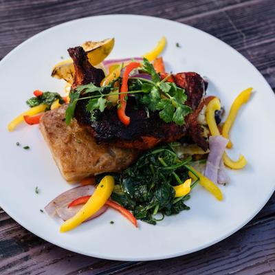 Chicken with sautéed spinach, sliced red and yellow bell peppers and red onion.