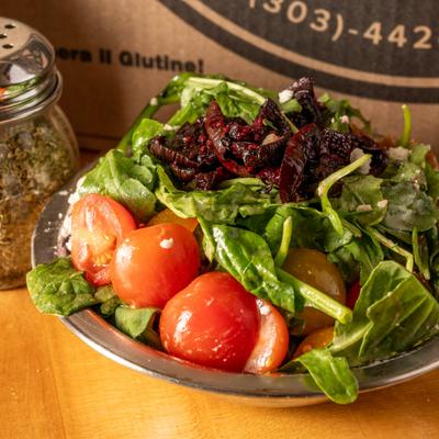 A vibrant spinach salad topped with tomatoes, walnuts, and beets.