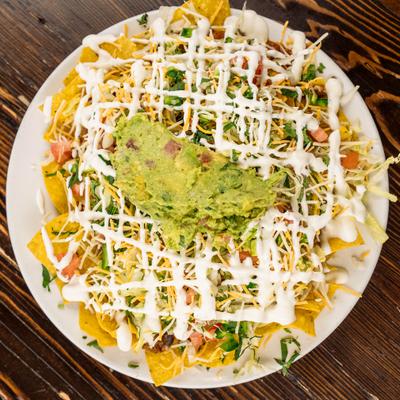 House nachos topped with guacamole and sour cream.