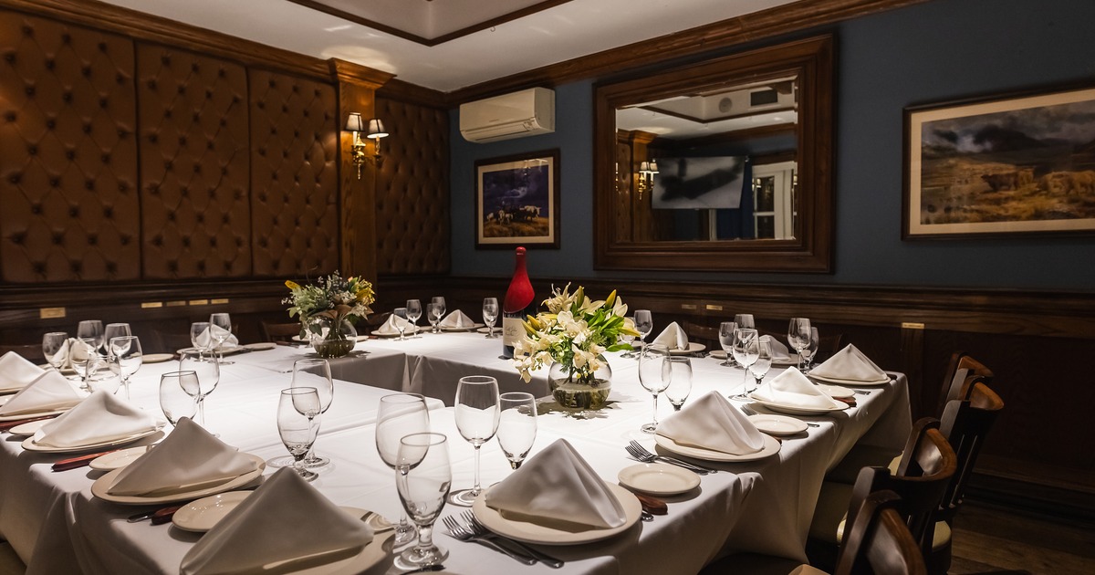 Private dining room set up for a formal event or dinner, with tables arranged in a square shape