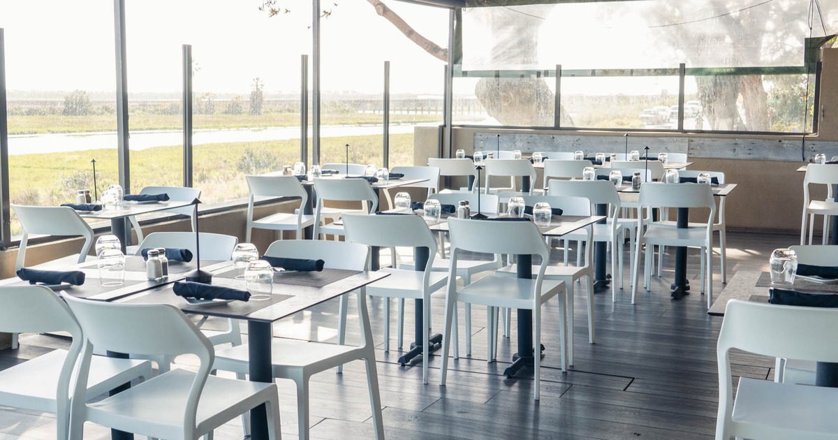 Large windows, seating area with white tables and chairs