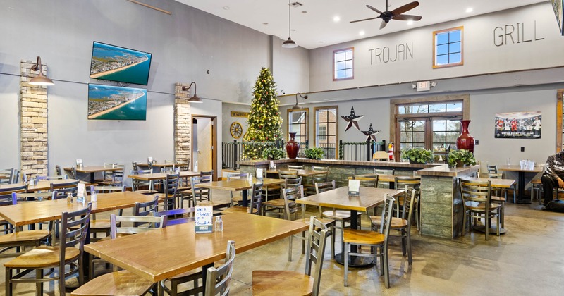 Dining area with wooden tables and chairs, Christmas tree and digital screens