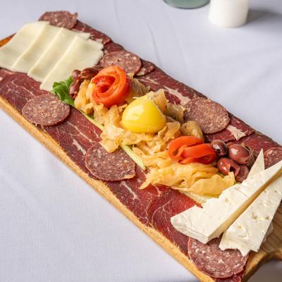Charcuterie board with meats, cheeses, olives, and pickled vegetables.