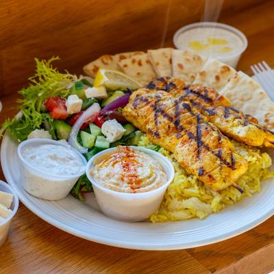 Grilled chicken with rice, grilled vegetables, pita, tzatziki, and hummus.