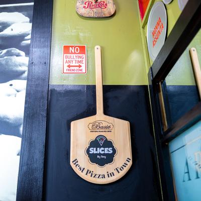 A wooden pizza peel with a logo for 