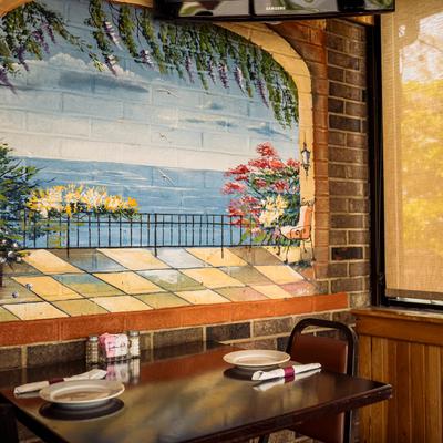 Two-top table, mural of a terrace with a sea view.