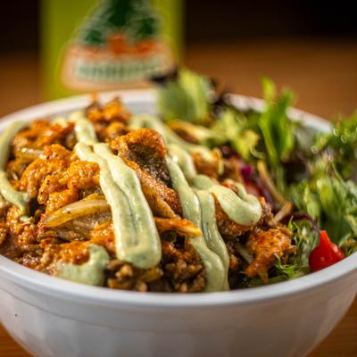 Feathered Feast meal bowl featuring seasoned meat and a side salad.