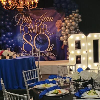 An elegant 80th birthday party featuring blue decor, marquee numbers, and custom backdrop.