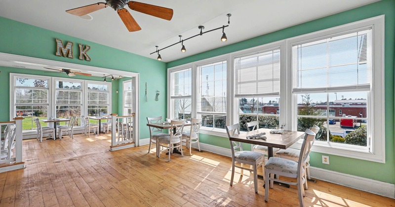 Bright café interior with mint green walls, large windows, and wooden floors