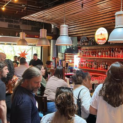 Crowded bar area with people seating and standing at the counter.