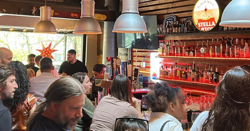 Crowded bar area with people seating and standing at the counter
