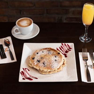 Blueberry pancakes served with orange juice and a cup of coffee.