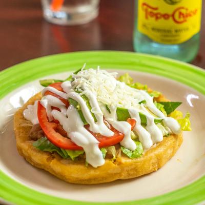 Fried masa dough, topped with pork, lettuce, tomato, avocado, cheese, and sour cream.
