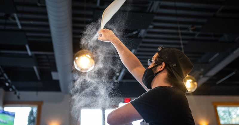 Cook tossing pizza dough in the air