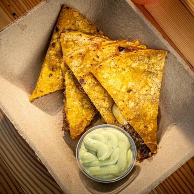 Quesadilla served with a side of avocado-based sauce.