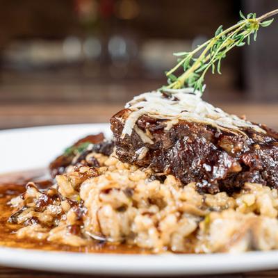 Braised short ribs served over a bed of mushroom risotto, garnished with fresh thyme.