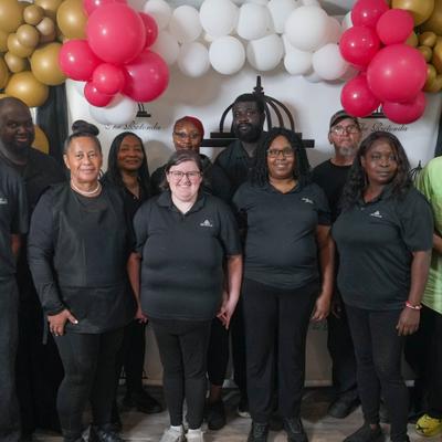 Staff posing beneath pink and white balloons.