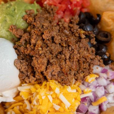 Ground beef with cheese, guacamole, olives, onions, close-up.