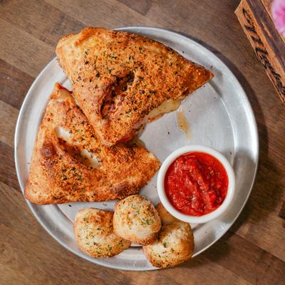 Meat lovers calzone with garlic knots and marinara sauce.