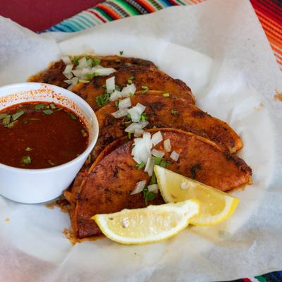 Quesabirria tacos, served with birria sauce.