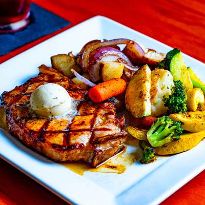 Grilled steak with sides of sauteed vegetables, and grilled potatoes and onions.