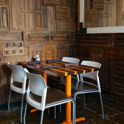 Restaurant table with chairs against a textured wooden wall.