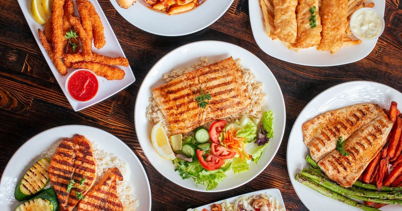 Various dishes featuring grilled fish, crispy calamari, fish tacos, shrimp pasta and fish and chips