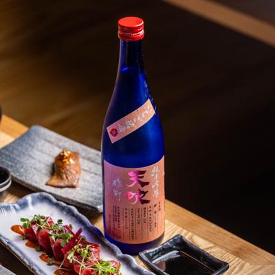 Blue bottle of sake beside tuna sashimi.