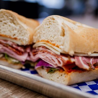 A close-up of a sandwich with ham, cheese, capocollo, and tomato.